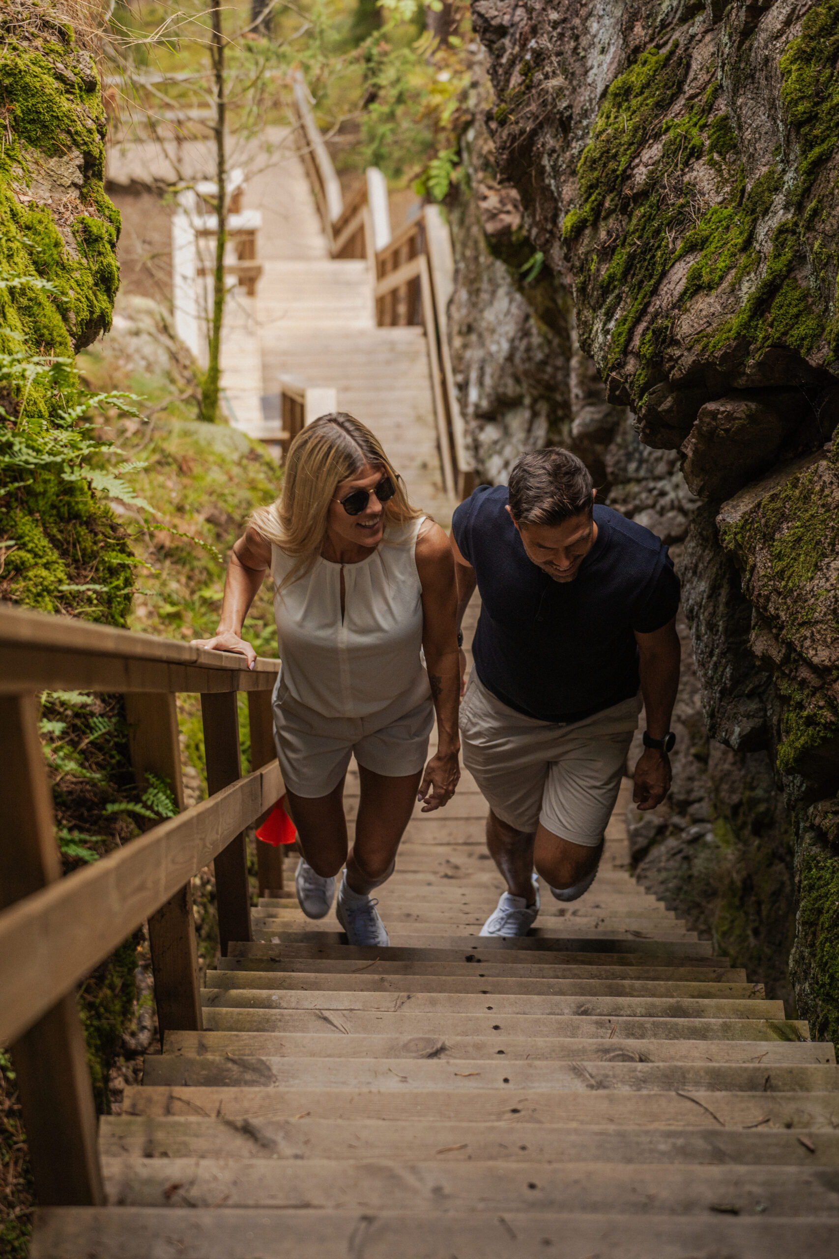 Ett par vandrar uppför trappan i Jättestigen på Isaberg mellan höga bergväggar.