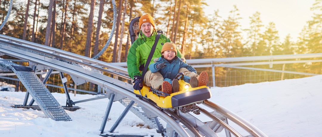 Pappa och barn åker rodelbanan på Isaberg en vinterdag