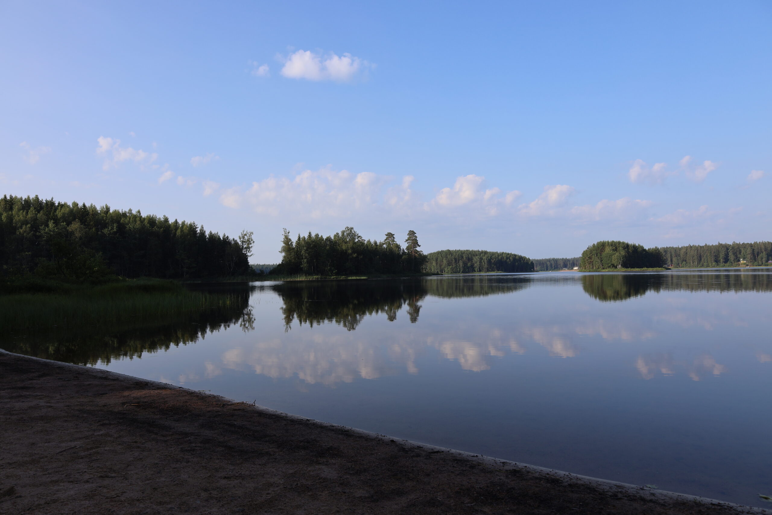 Sandstranden på Viksbadplats med utblick över Vikaresjön med skogbeklädda öar vid Hestraviken