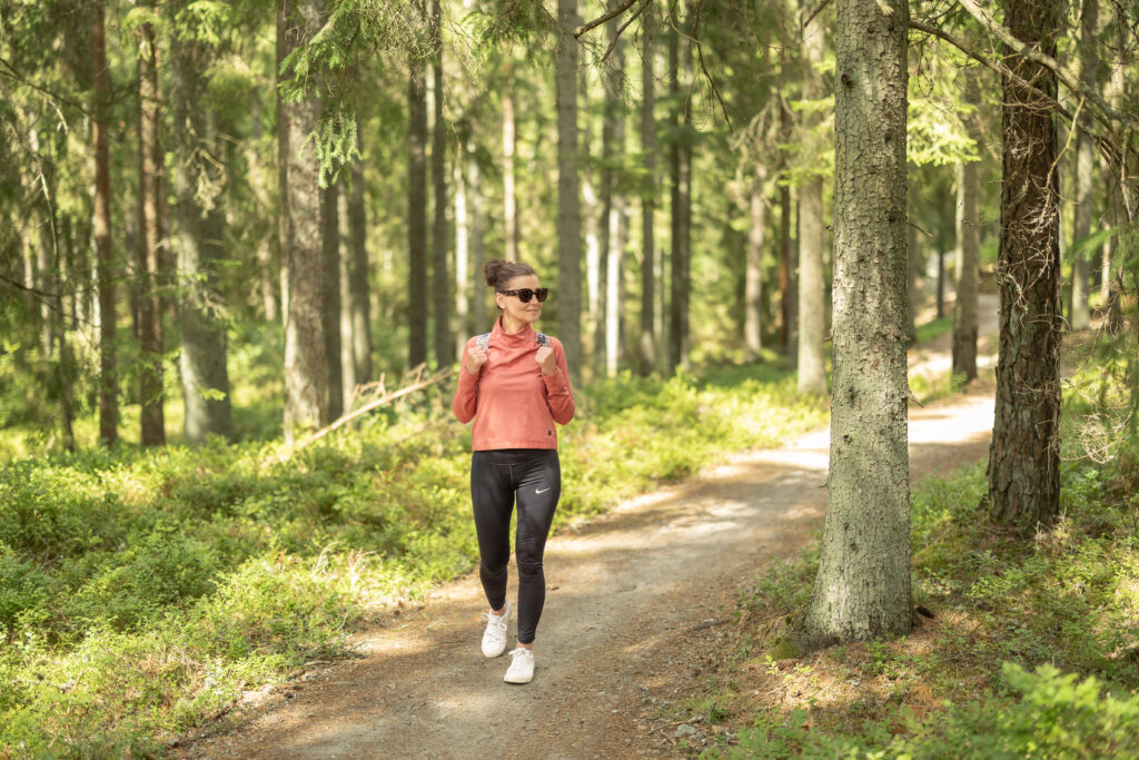 Kvinna som vandrar på Pink Lady-leden genom skogen runt Algustorpasjön nära Hestraviken.