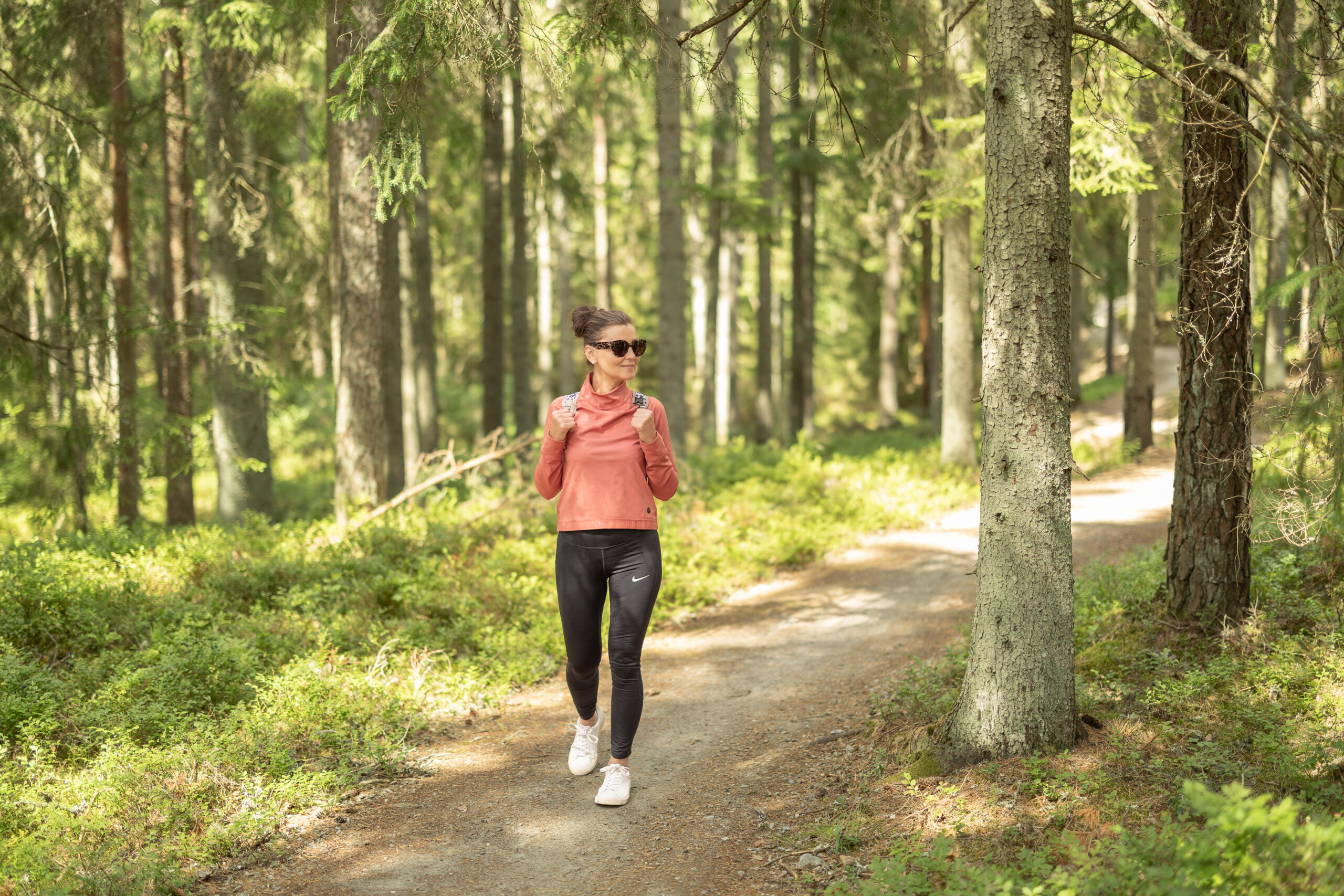 Kvinna som vandrar på Pink Lady-leden genom skogen runt Algustorpasjön nära Hestraviken.
