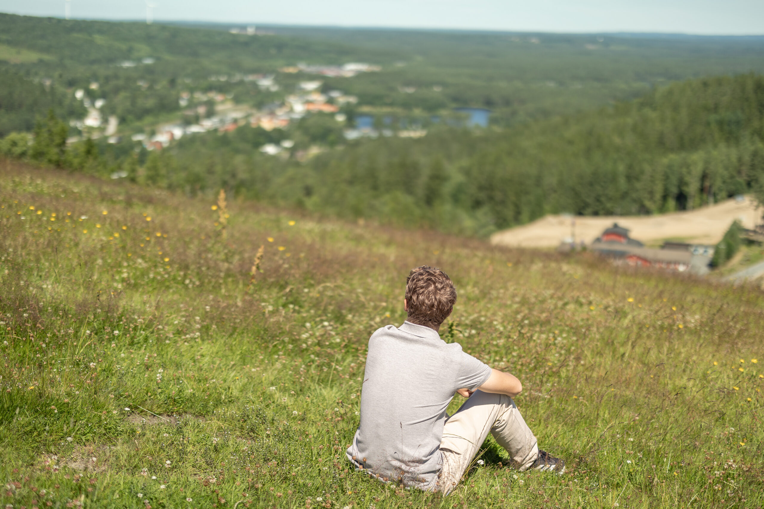 Person som sitter på toppen av Isaberg och blickar ut över Smålands skogar och dalgångar efter vandringen på Jättestigen.